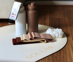 Brown resistance bands on a white mat with 'SOULAR' branding, next to a brown water bottle and smartphone.
