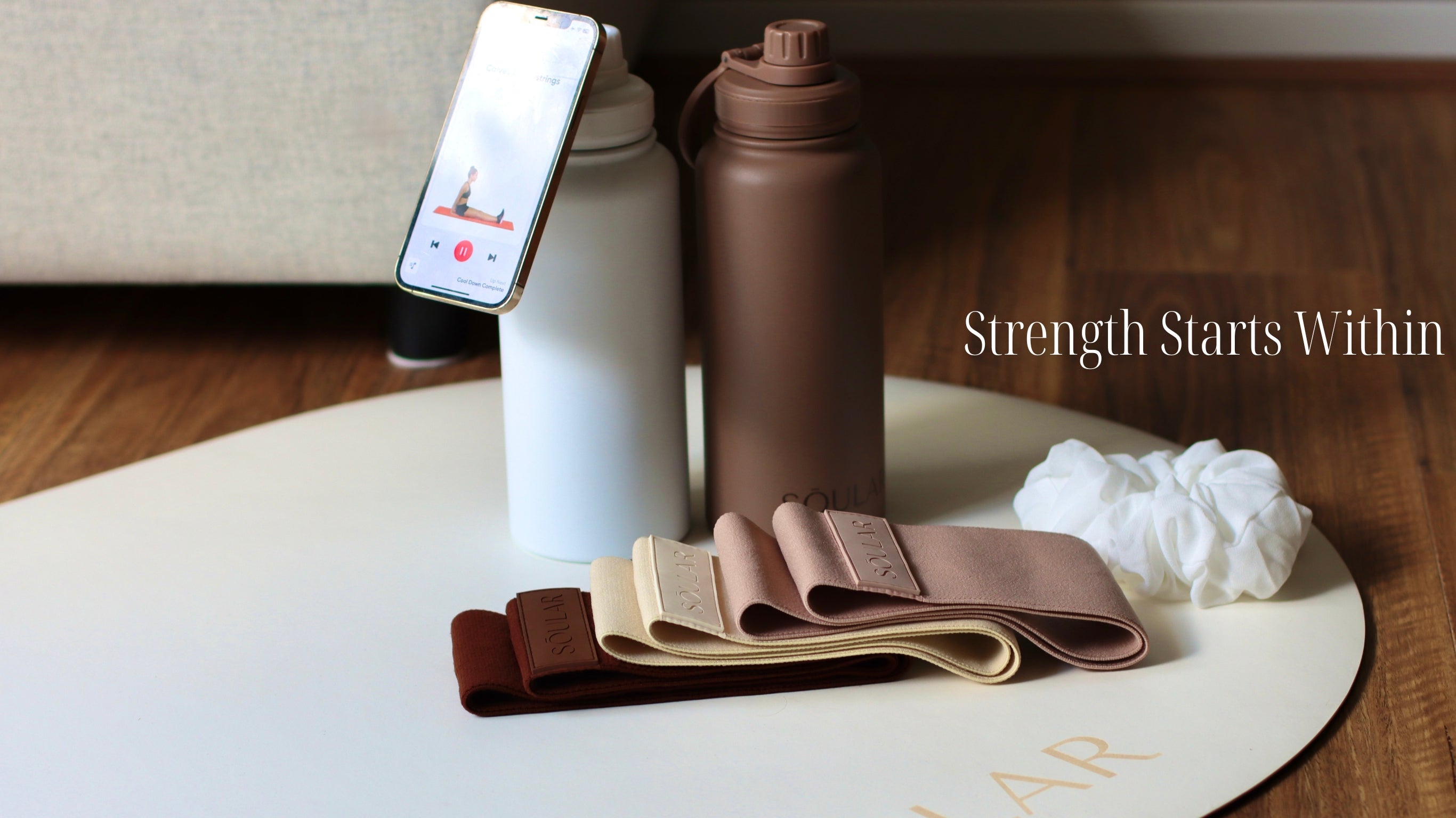 Yoga mat, resistance bands, and water bottles on a white mat with 'Strength Starts Within' text.